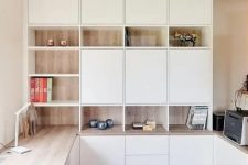 a minimalist home office with white and stained storage units, with a built-in desk and some pretty decor is very chic