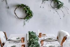 a minimalist tablescape with a lush greenery garland, copper touches and greenery wreaths on the wall