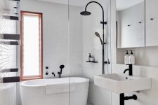 a modern bathroom with white and black and white tiles, an oval tub, a sink, a mirror cabinet and black fixtures