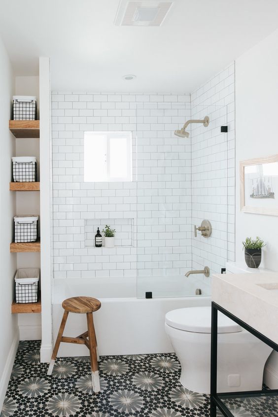 a modern bathroom with white subway and black printed tiles, a vanity with a sink, a niche with shelves and a stool