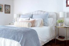 a modern farmhouse bedroom with wooden beams on the ceiling, a white bed with pastel blue and white bedding, tiered nightstands and a printed rug