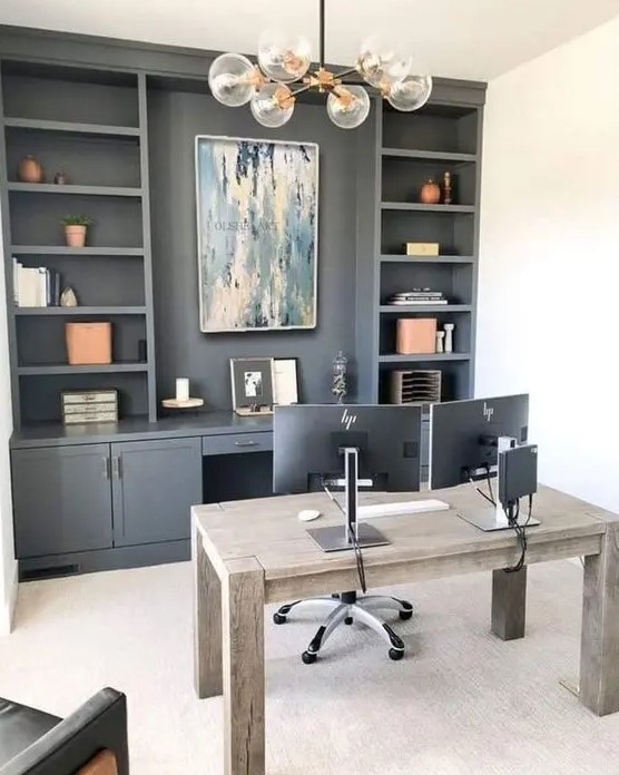 a modern farmhouse home office with a grey storage unit, with open shelves and cabinets, a stained wooden desk, a chair and a bubble chandelier