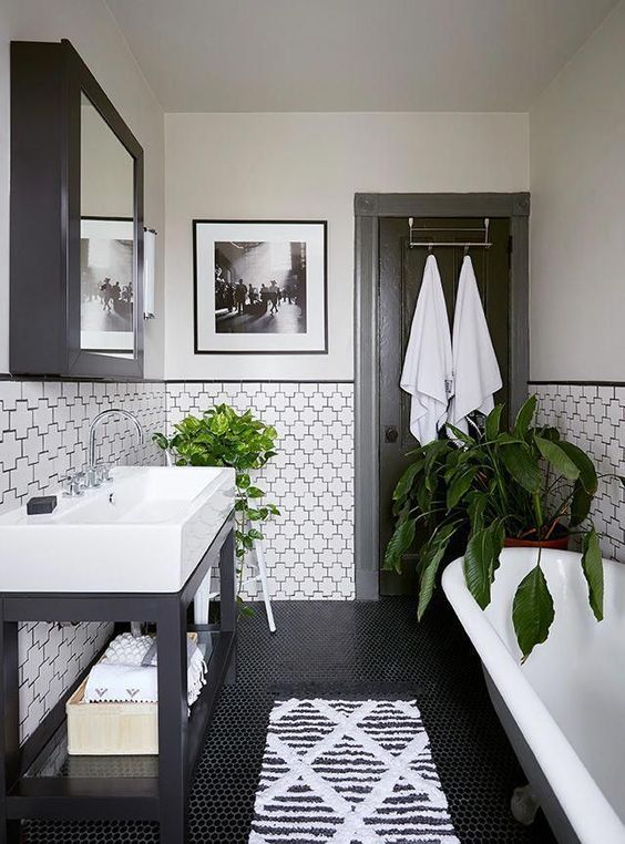 a modern monochromatic bathroom with printed tiles, a large sink, a vintage bathtub, a mirror cabinet and greenery