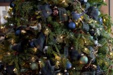 a moody Christmas tree with navy plaid ribbons, navy and green ornaments, branches, moss, greenery and pinecones is very woodland-like