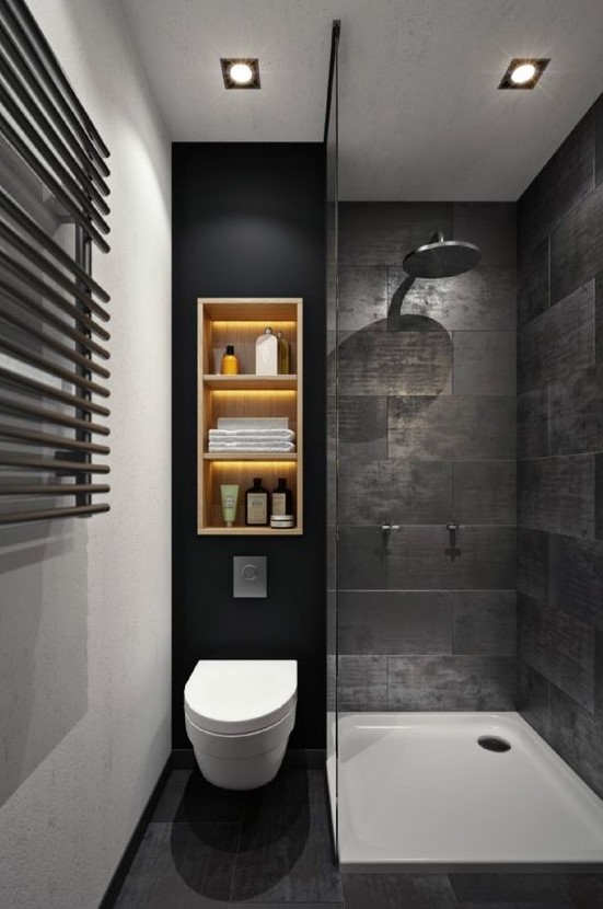 a moody black bathroom with stone-inspired tiles, a wall shelf with lights, a shower space