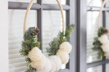 a neutral and simple Christmas wreath of an embroidery hoop, fir branches, pinecones and white pompoms is all you need
