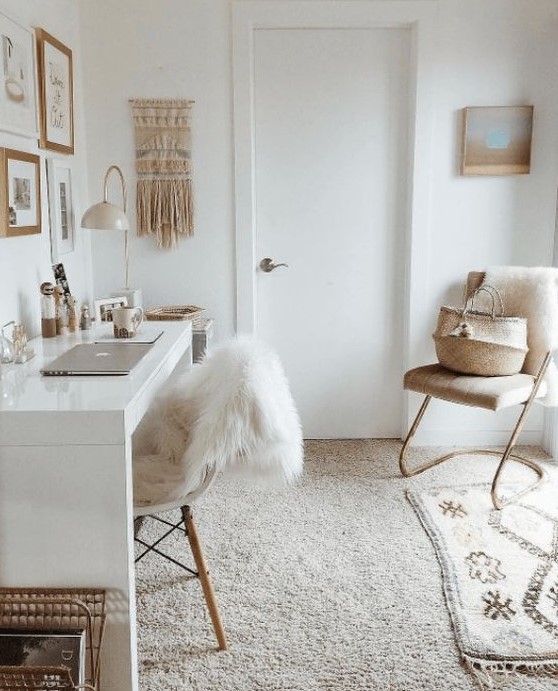 a neutral boho home office with a gallery wall, a white desk, layered rugs and a macrame hanging looks relaxing