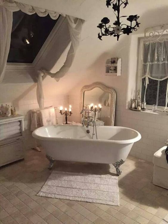 a neutral vintage bathroom with a clawfoot tub, a floral chandelier, neutral curtains and a mirror in a chic frame