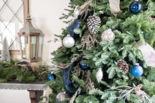 a pretty Christmas tree with silver and blue ornaments, a navy plaid ribbon, pinecones, twigs and wooden beads is very chic