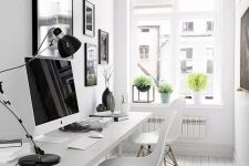 a pretty white Nordic home office with a black and white gallery wall, a white shared desk, white chairs and potted greenery