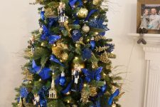a refined and bold Christmas tree with lights electric blue and gold ornaments, butterflies fabric and paper blooms