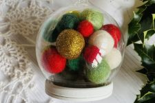 a sheer glass ornament with colorful pompoms inside is a very creative and bright decoration for winter holidays