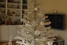 a shiny silver Christmas tree with white and silver ball and snowflake ornaments can be a nice tabletop decoration or an additional tree in some room