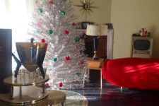 a silver Christmas tree with emerald and red ornaments plus a vintage topper is a bold and lovely idea for a vintage space