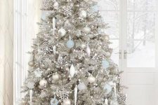 a silver Christmas tree with white, silver and blue ornaments, rhinestone snowlakes and some lights feels frozen