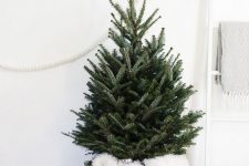 a small Christmas tree with no decor, in a basket with faux fur and vintage lights is a beautiful idea for a Nordic feel