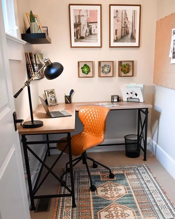 a small and cool home office with a memo board, a corner desk, a boho rug, a gallery wall and a table lamp