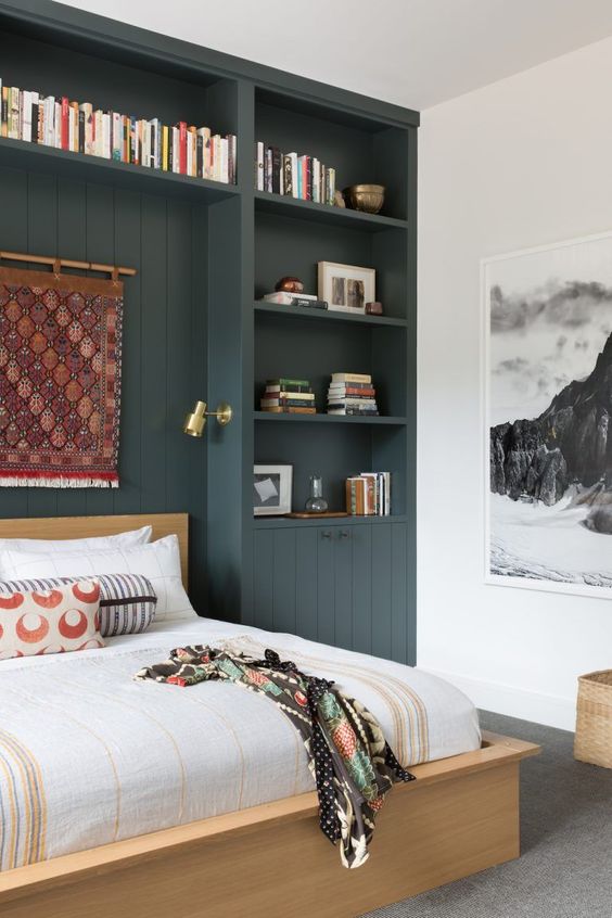 a small and smartly organized bedroom with a soot storage unit, a bed, an artwork and printed bedding