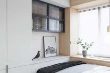 a small bedroom looks larger thanks to the neutral color scheme, a large window by the bed and floor to ceiling furniture