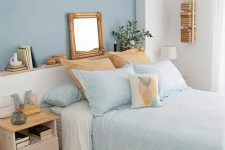 a small bedroom with a blue accent wall, a bed with aqua and white bedding, a pastel nightstand and wooden touches