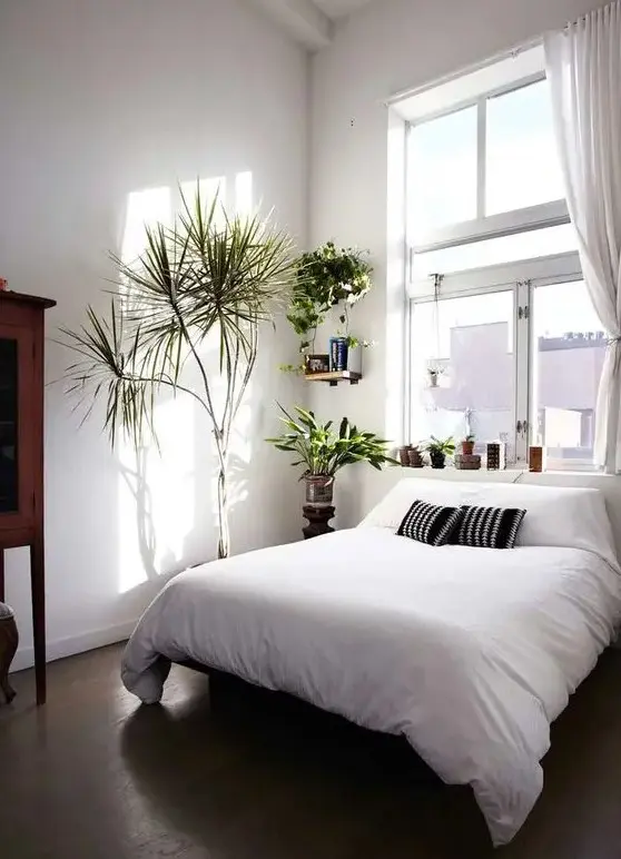 a small bedroom with a window over the bed that fills the whole space with natural light, white walls help with that, too