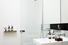 a small minimal shower space with a glass space divider, a wall-mounted sink, a stump stool and some lights