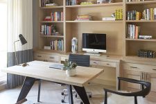 a small modern home office with a built-in storage unit, a desk, black chairs, books and a PC