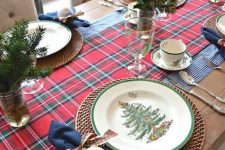 a stylish Christmas tablescape with rustic touches – a burlap runner, woven placemats, navy napkins and printed ornaments and foliage and fir branches