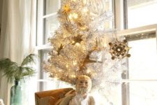 a tabletop silver Christmas tree with lights and vintage gold ornaments and white faux fur to cover it up is a stylish idea