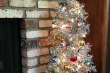 a vintage silver Christmas tree with lights, colorful ornaments, a vintage crate with ornaments is a lovely idea for refined holiday decor