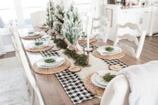 an airy farmhouse Christmas table with a burlap runner, woven chargers, wood slices with monograms, flocked mini trees and candkes