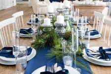 an elegant navy and silver Christmas tablescape with navy linens, fir branches and vintage candlehodlers with cndles
