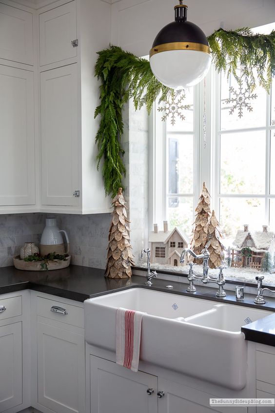 an evergreen garland with snowflakes on the window will make it feel like holidays, it looks cool and chic