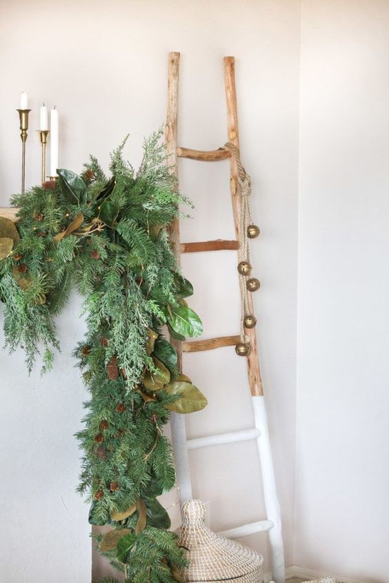 beautiful Christmas decor with a lush fir garland with leaves and pinecones, a color block ladder with bells is amazing