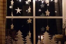 beautiful Christmas window decor with a branch, stars and lights and some decor on the windowsill