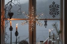 beautiful Christmas window styling with snowflakes, branches and some candles on the windowsill