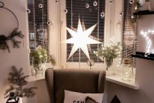 beautiful bow window Christmas decor with silver ornaments, lights, evergreens and a large star lamp is cool