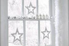 beautiful white and silver Christmas window decor with ornaments, candle lanterns, twine stats and squirrels is magical