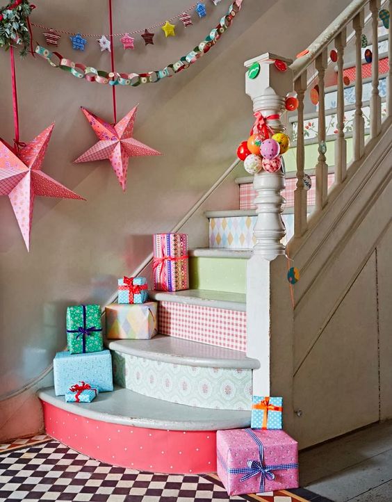bright Christmas staircase decor with bold wallpaper, brightly wrapped gift boxes, bold stars and paper garlands on the wall