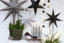 classy Scandinavian Christmas decor with oversized cardboard stars, black and gold lights, faux fir, a small tree and branches