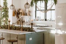 cozy Christmas decor with evergreens, bell and wood garlands is a cool idea for a kitchen, you can make some yourself