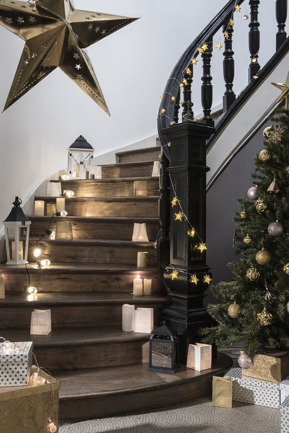 elegant Christmas staircase decor with candle lanterns, mini lanterns of paper, star garlands and an oversized star on the wall
