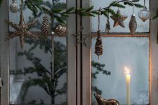 elegant Christmas window decor with an evergreen garland with gold ornaments and clear ones