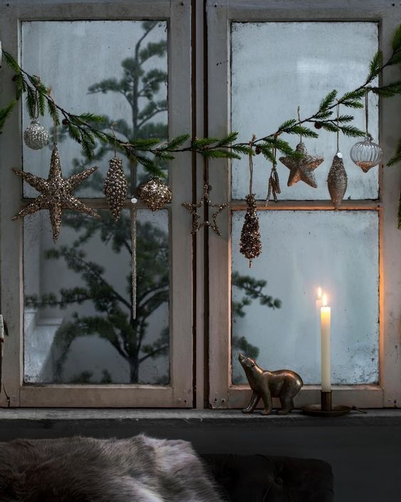 elegant Christmas window decor with an evergreen garland with gold ornaments and clear ones