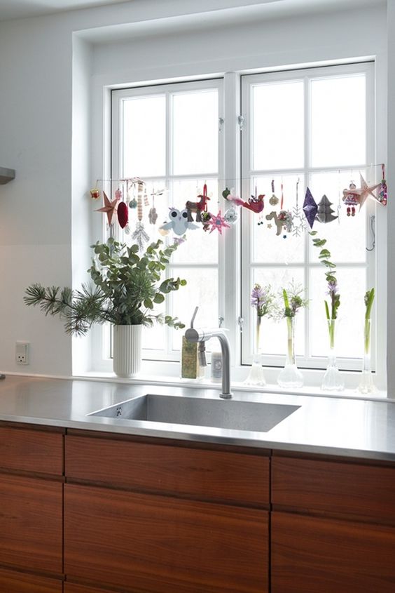 kitchen Christmas window styling with various ornaments hanging over the countertop is a cool idea