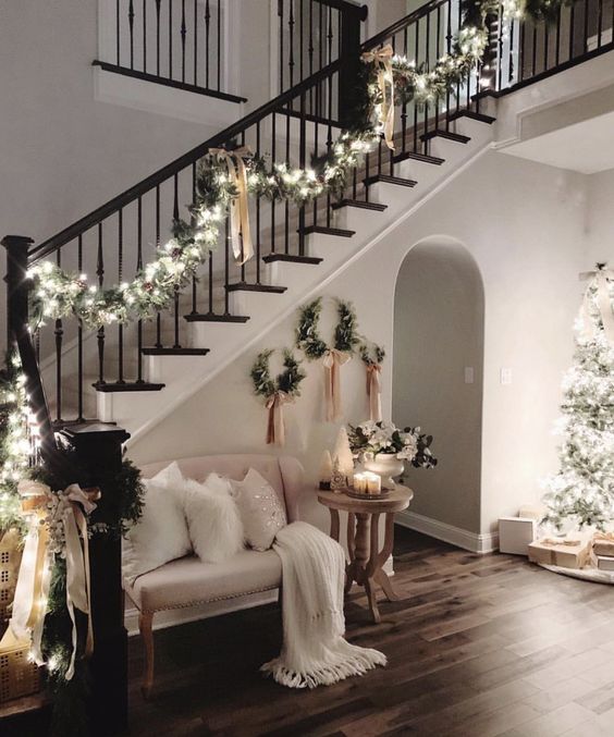 lovely and chic Christmas railing decor with an evergreen garland with lights and tan bows is pure elegance and looks very glam
