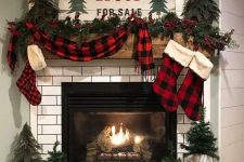 lovely rustic Christmas mantel with a plaid scarf and stockings, mini Christmas trees on the mantel and around the fireplace