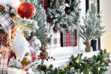 lush Christmas decor with a plaid art and a snowy wreath,, a greenery and berry garland, a flocked Christmas tree with red gltter and silver ornaments