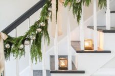 mini glass candleholders, an evergreen garland with silver ornaments and tan bows on the railing for elegant modern Christmas decor