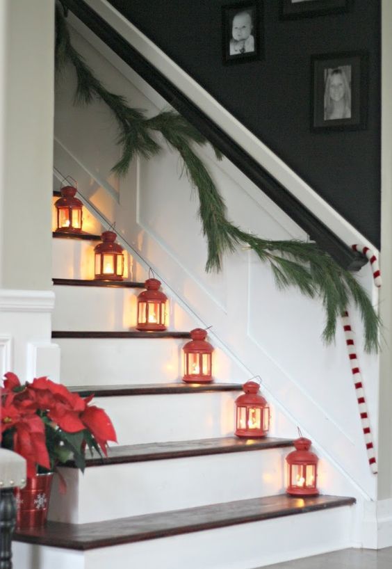 mini red candle lanterns on each step, poinsettia arrangements, a fir garland and candy canes on the railing for Christmas